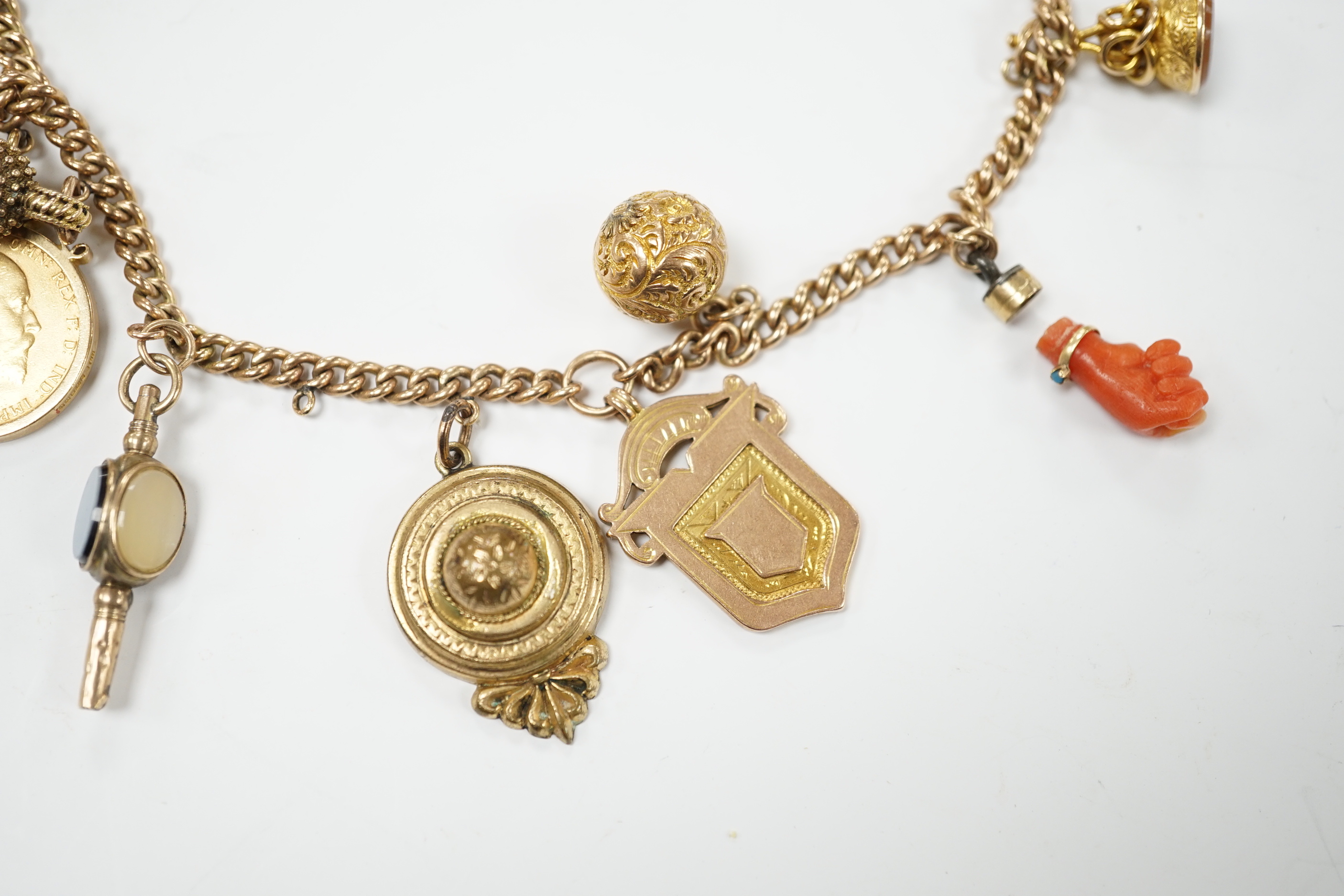 A 9ct gold curblink chain hung with fifteen assorted charms including a 1906 sovereign and an 1865 20 francs coin, gross 80.8 grams